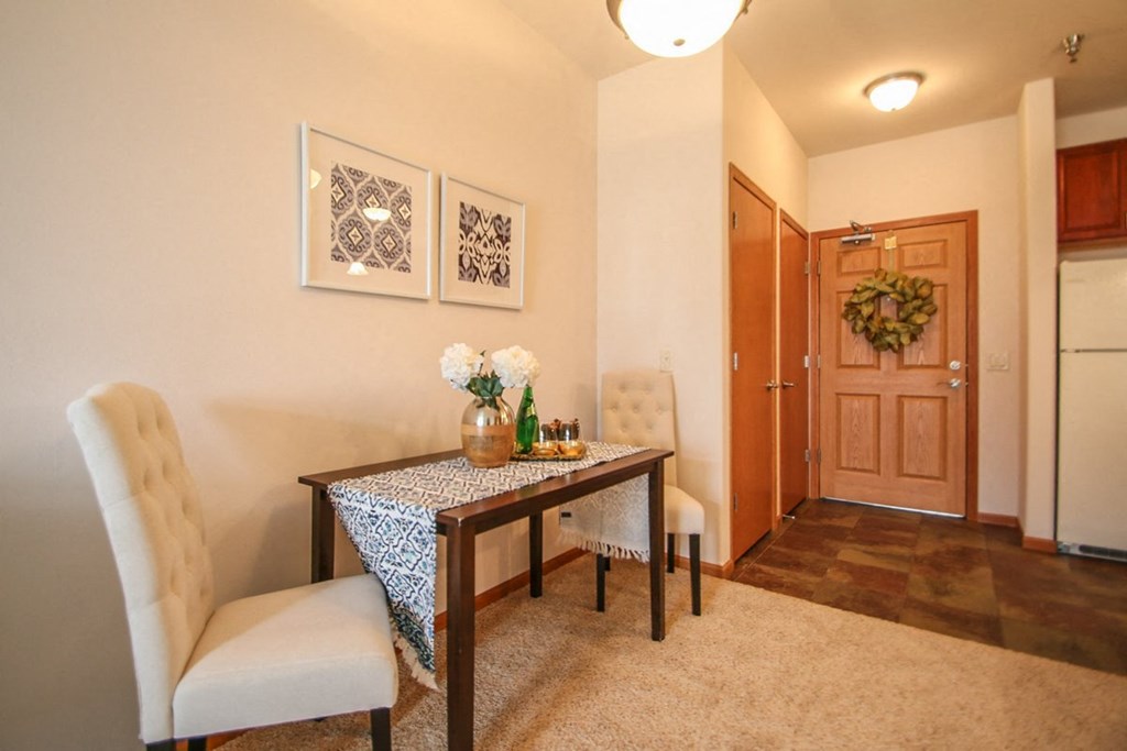 a dining room with a table and chairs and a hallway with a refrigerator