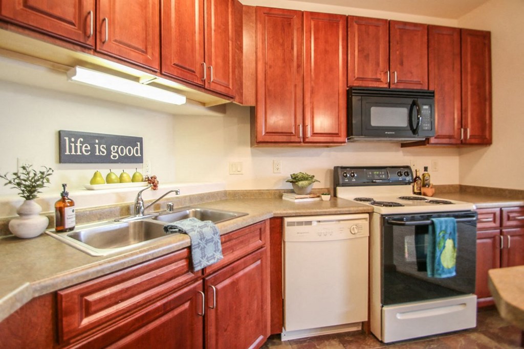 a kitchen with wooden cabinets and white appliances and a sink