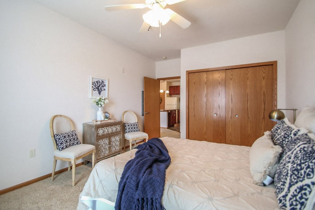 a bedroom with a bed and two chairs and a closet