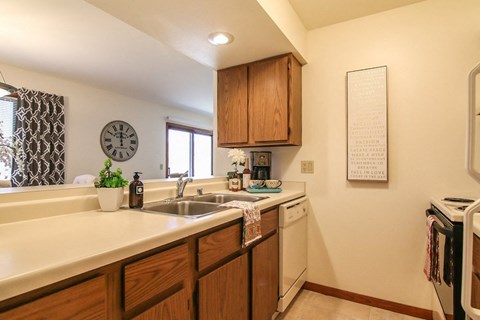 a kitchen with a sink and a dishwasher and a clock on the wall