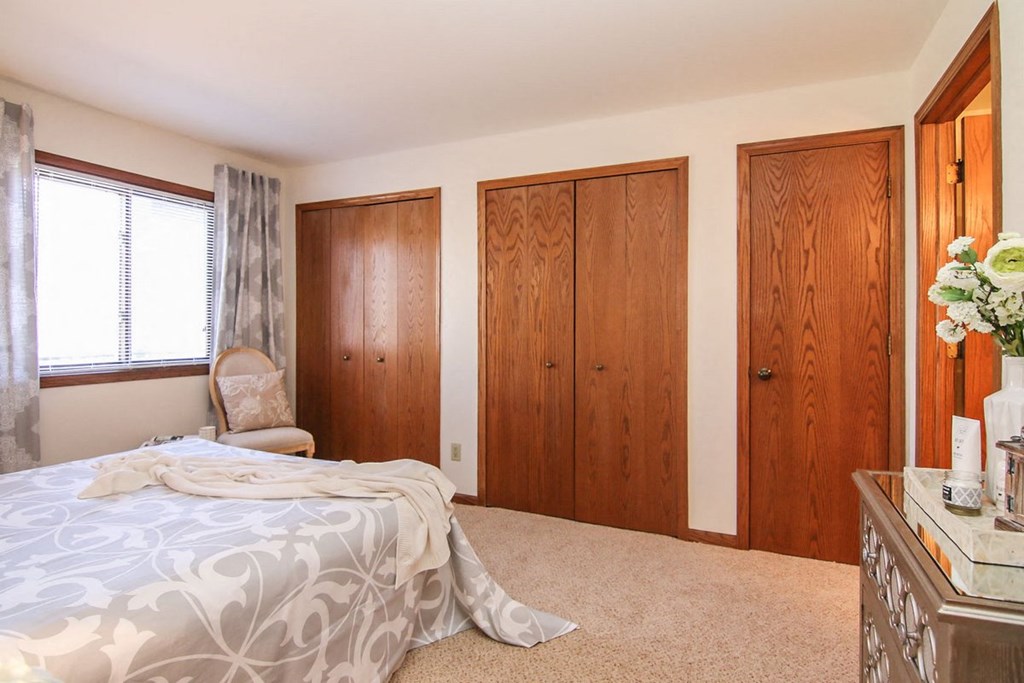 a bedroom with a bed and two closets and a chair