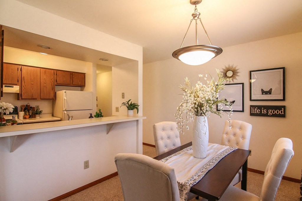 a dining room table with chairs and a vase of flowers