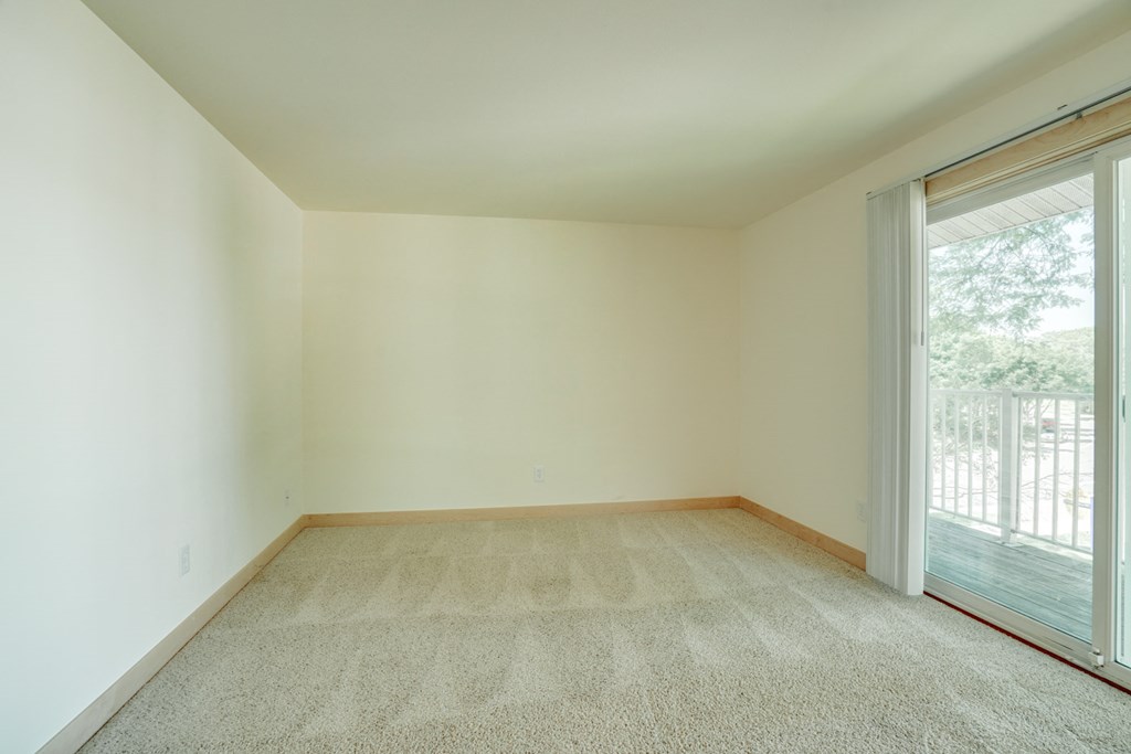 an empty living room with a large window and carpet