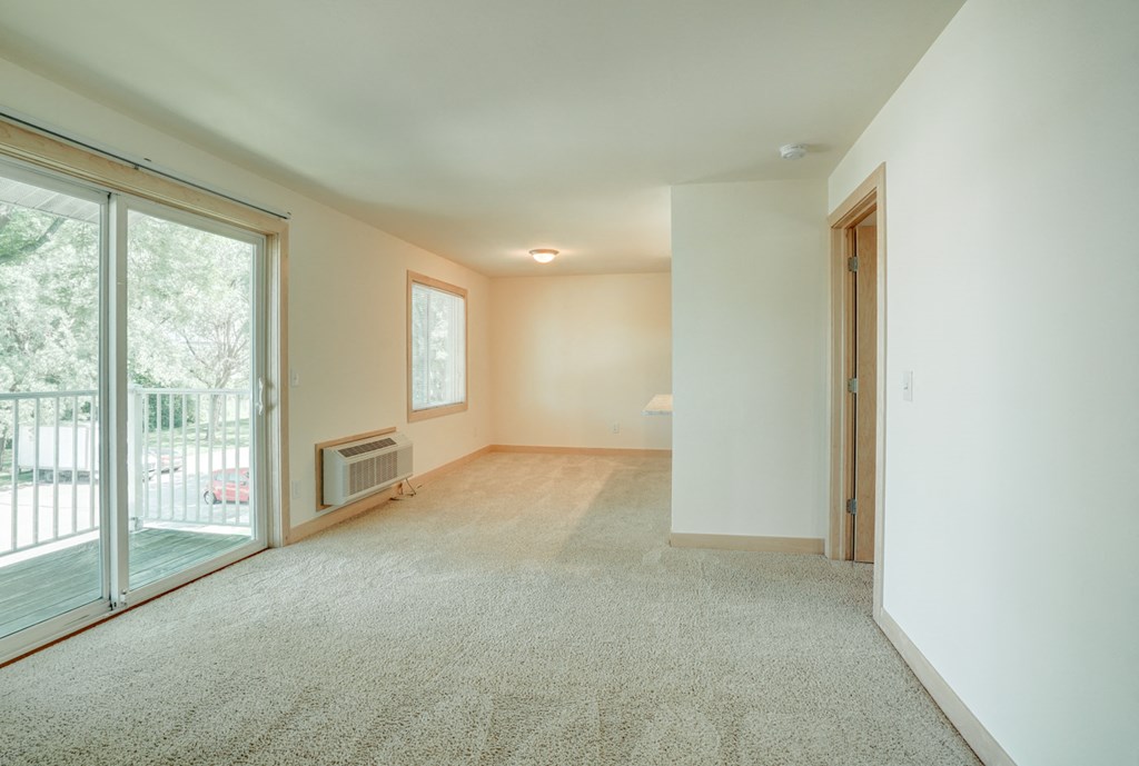 an empty living room with a sliding glass door to a balcony