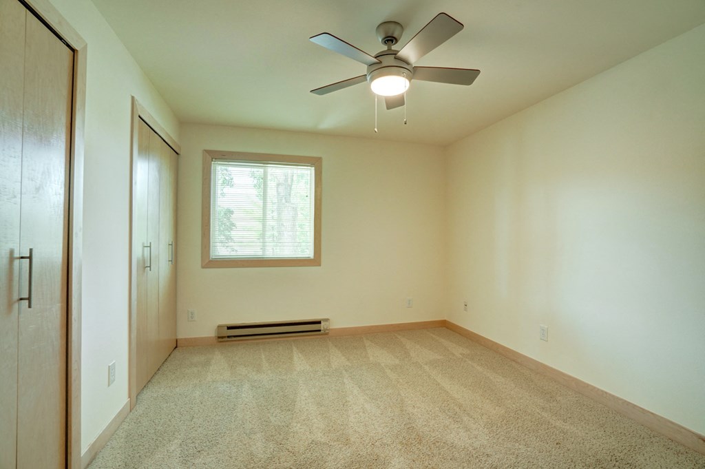 an empty living room with a ceiling fan and a window