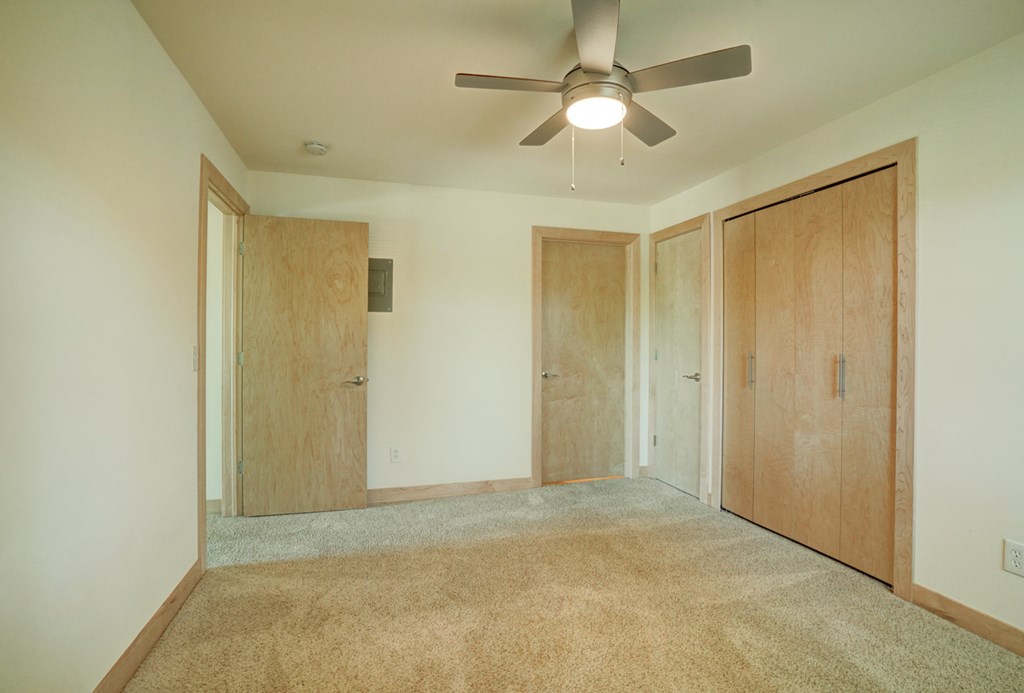 an empty room with a ceiling fan and two doors