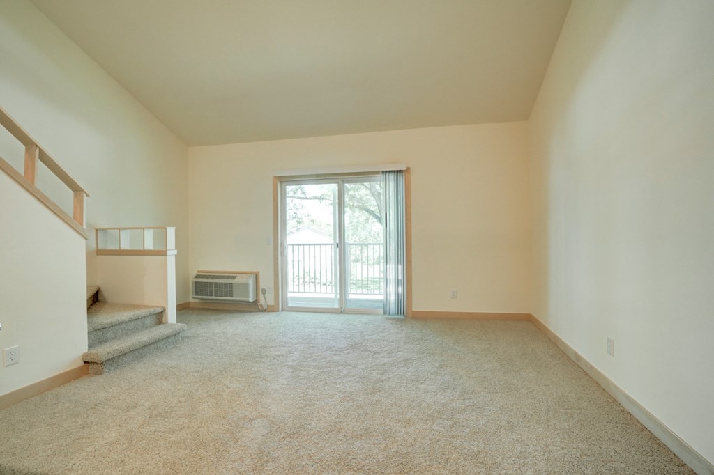 an empty living room with a door to a balcony