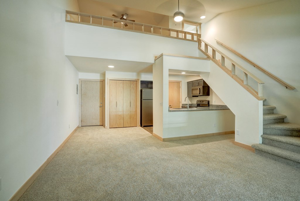 a living room with a staircase and a kitchen in a house