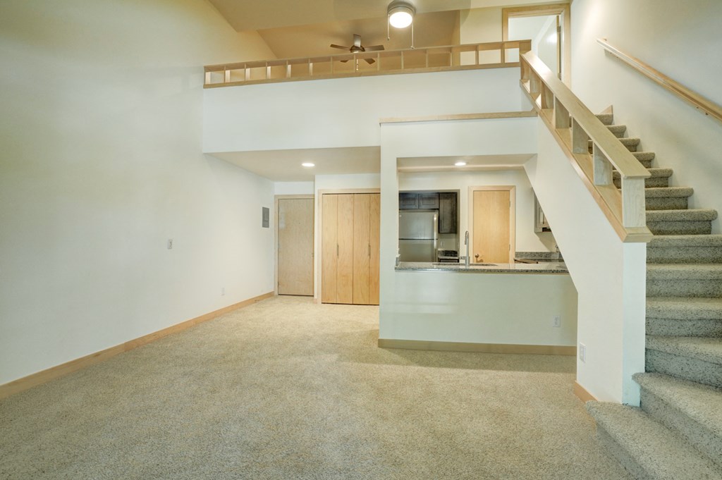 a living room with a staircase and a kitchen in a house