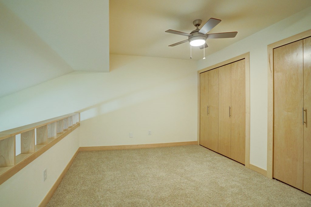 an empty bedroom with a ceiling fan and a closet