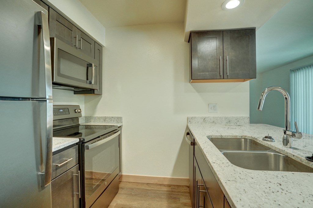 an empty kitchen with stainless steel appliances and granite counter tops