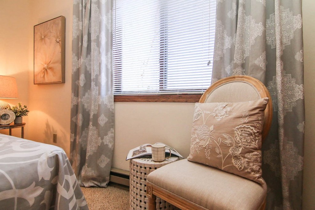 a bedroom with a chair and a window with curtains