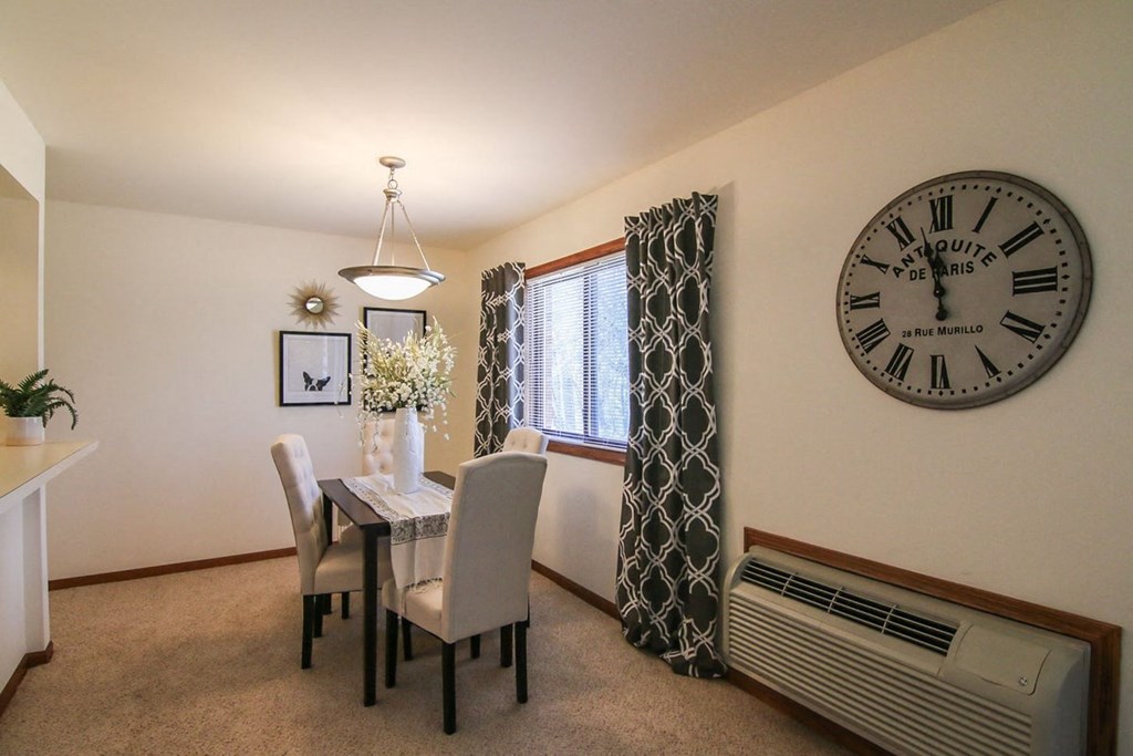 a dining room with a clock on the wall and a table and chairs