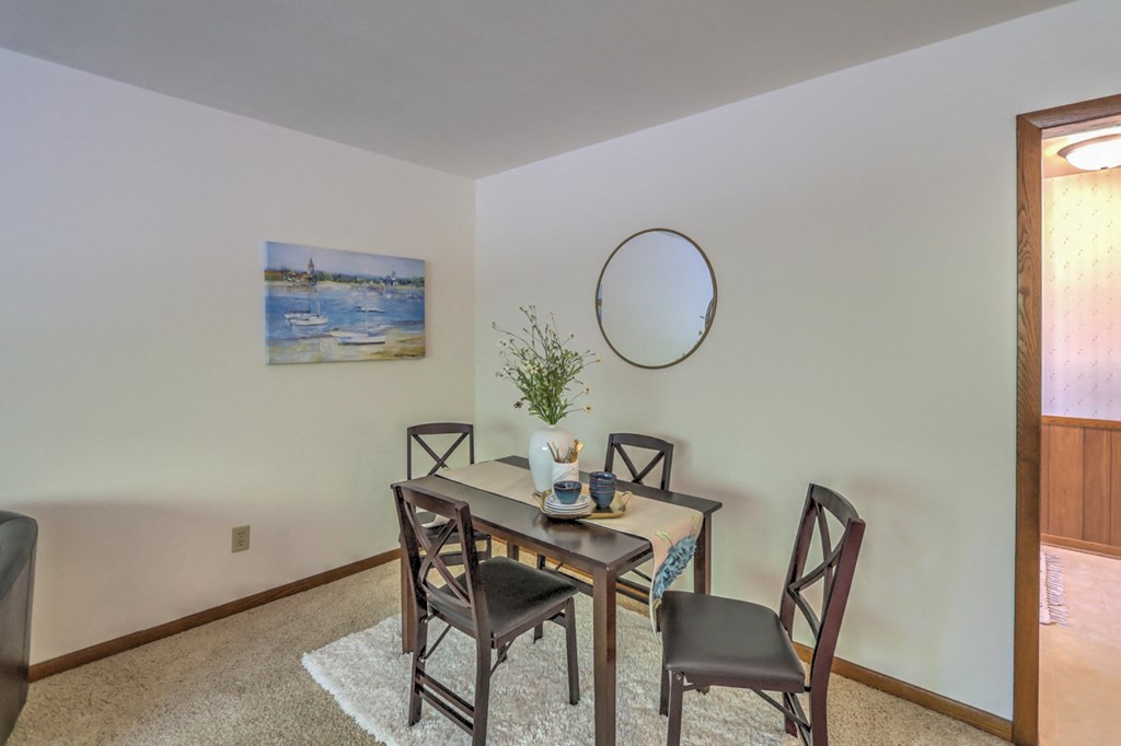 a dining room with a table and chairs and a round mirror