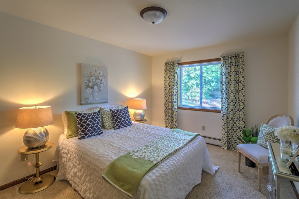 a bedroom with a bed and two lamps and a window