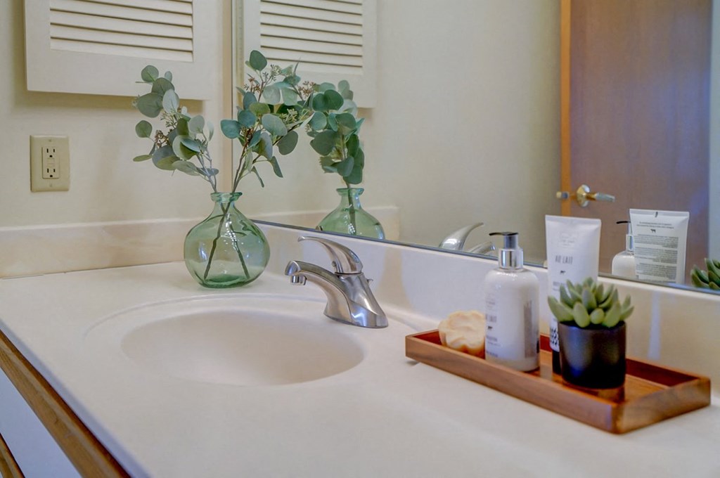 a bathroom sink with a vase with flowers on it