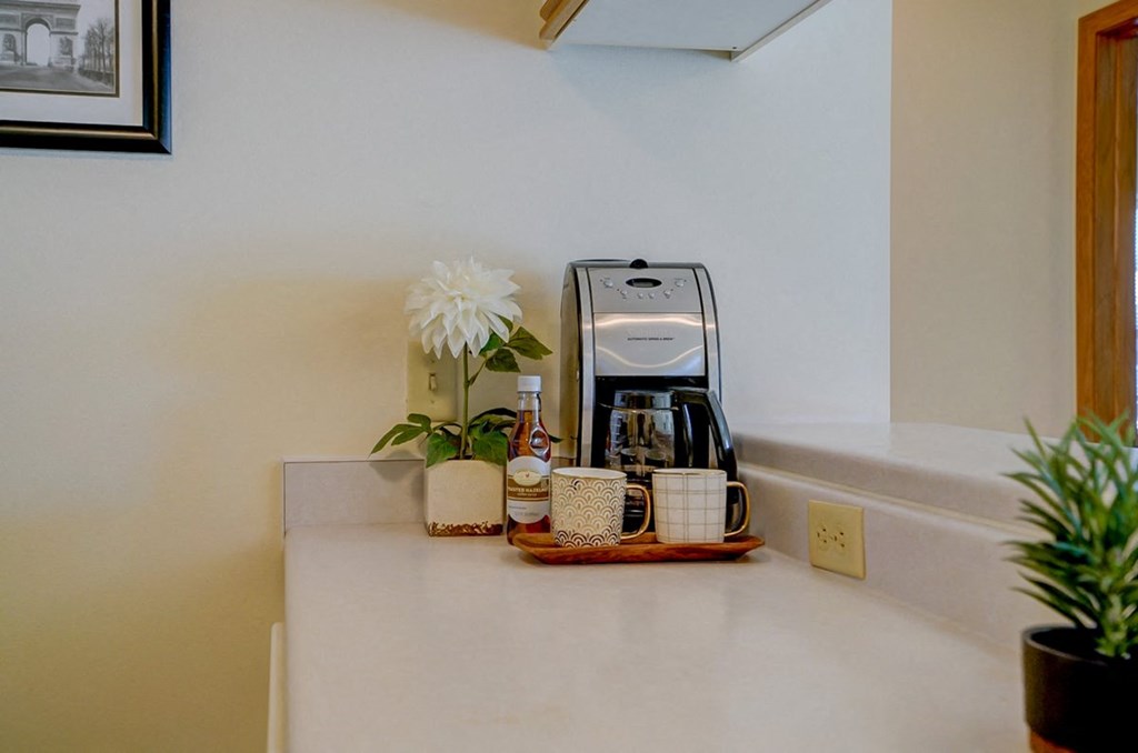 a kitchen counter with a coffee maker and coffee cups on it