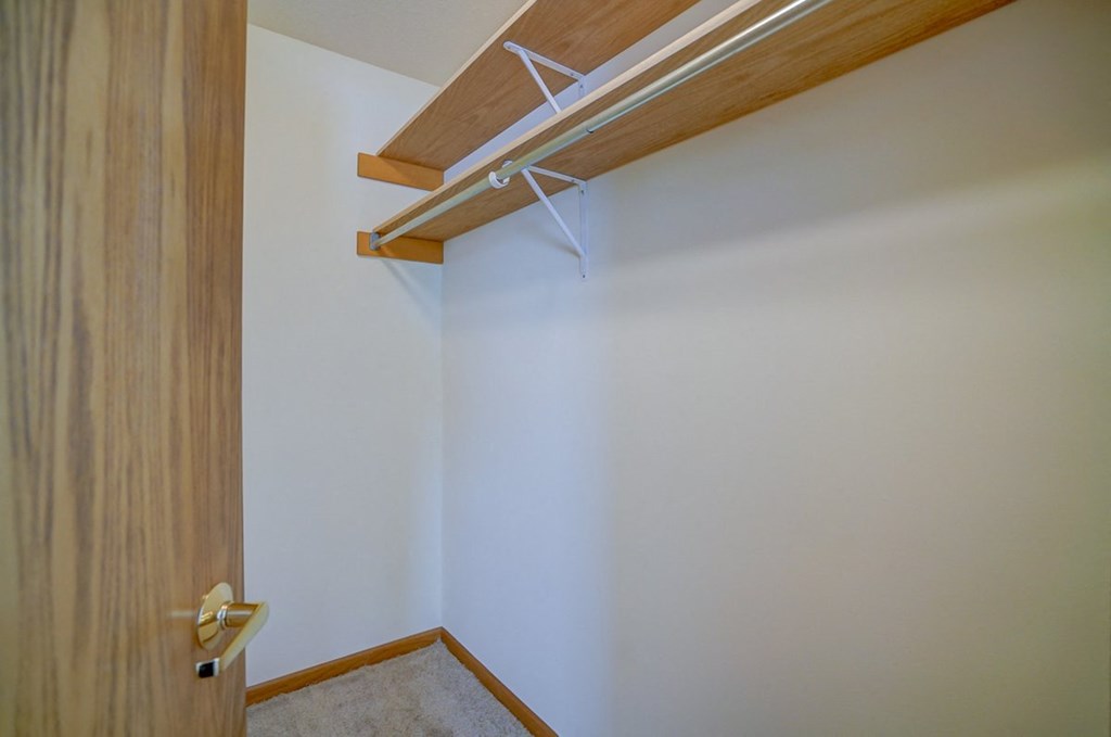a walk in closet with a wooden door and white walls