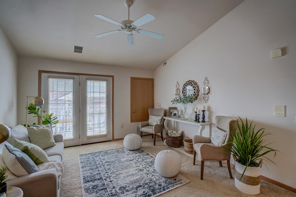 a living room with couches and chairs and a ceiling fan