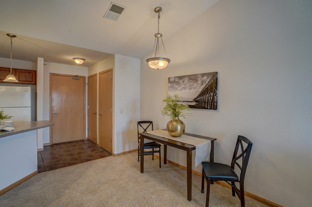 a dining room with a table and chairs and a kitchen with a refrigerator