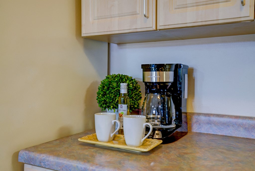 a coffee maker and two cups on a kitchen counter