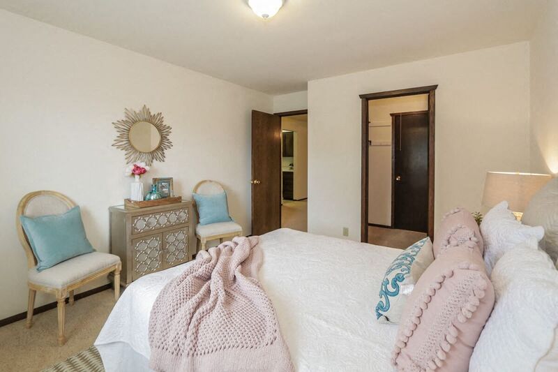 a bedroom with a bed and two chairs and a mirror