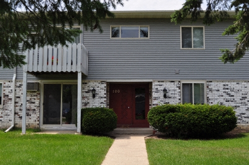 the front of a gray house with a red door