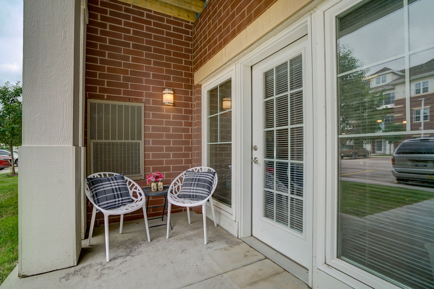 a patio with two chairs and a table outside of a brick house