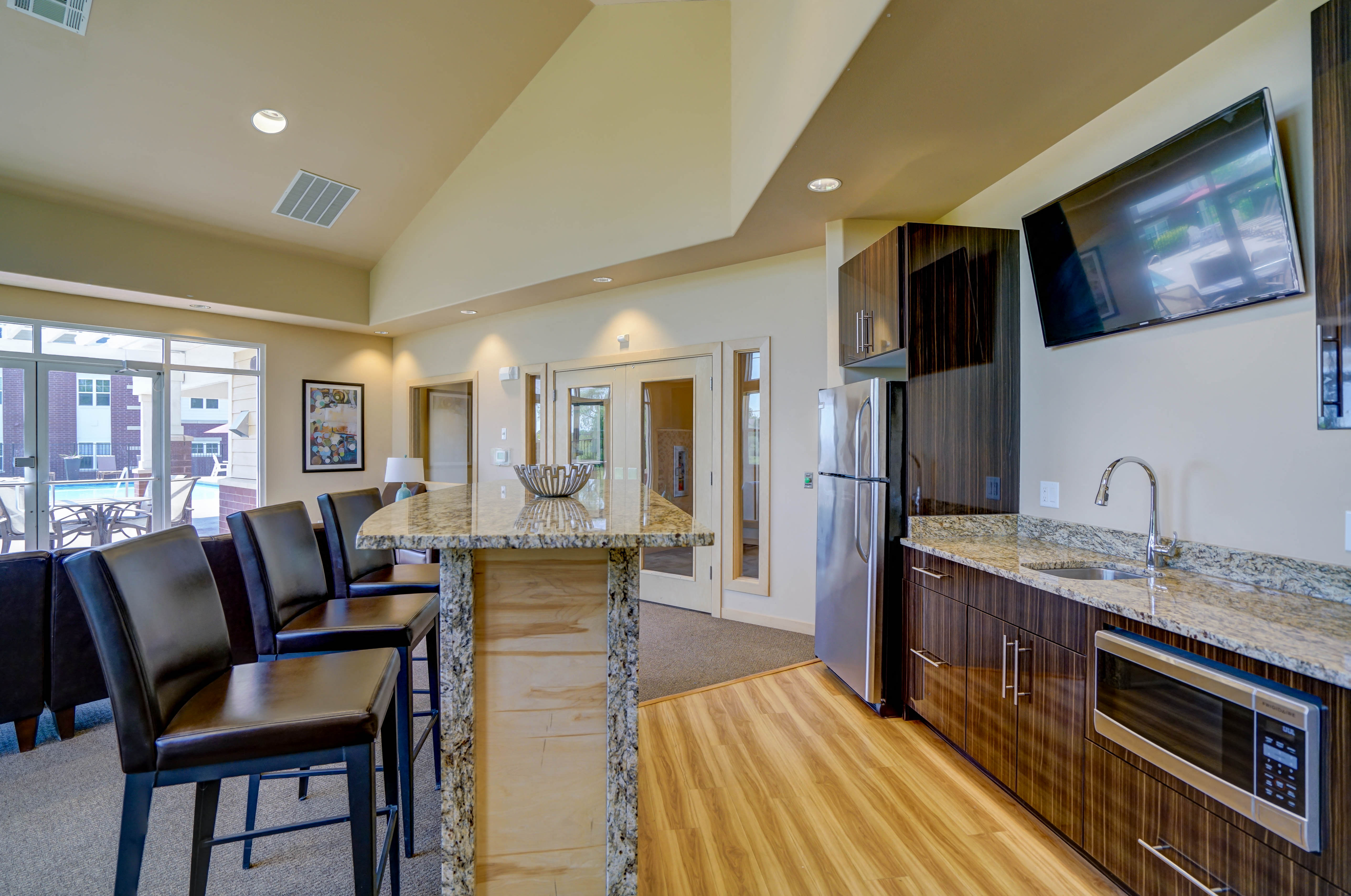 a kitchen with granite counter tops and a bar with chairs