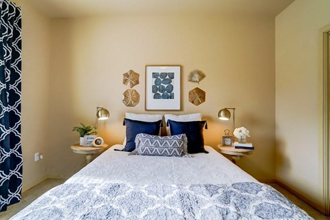 a bedroom with a bed with blue pillows and a blue and white bedspread
