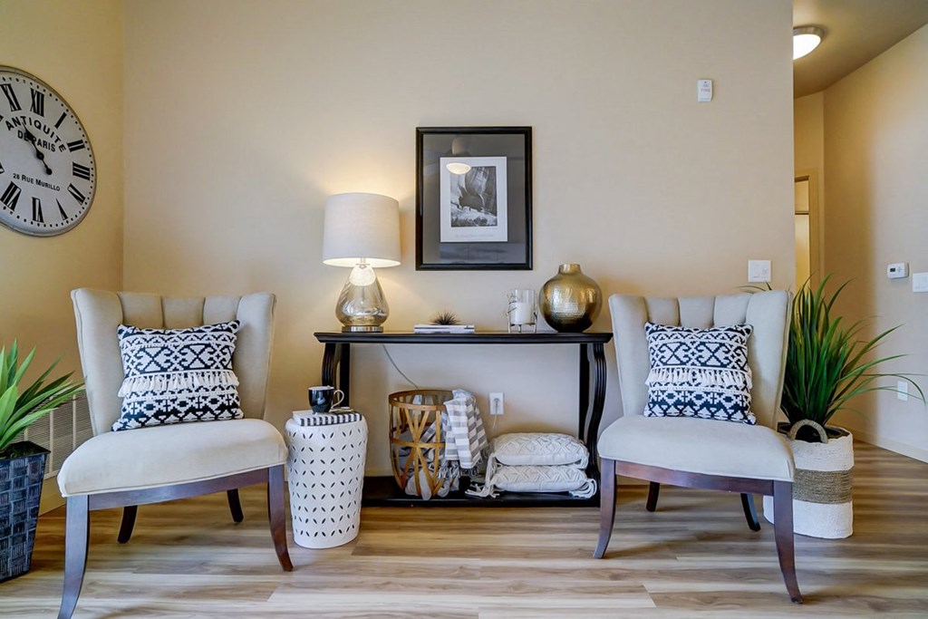 a living room with two chairs and a table and a clock