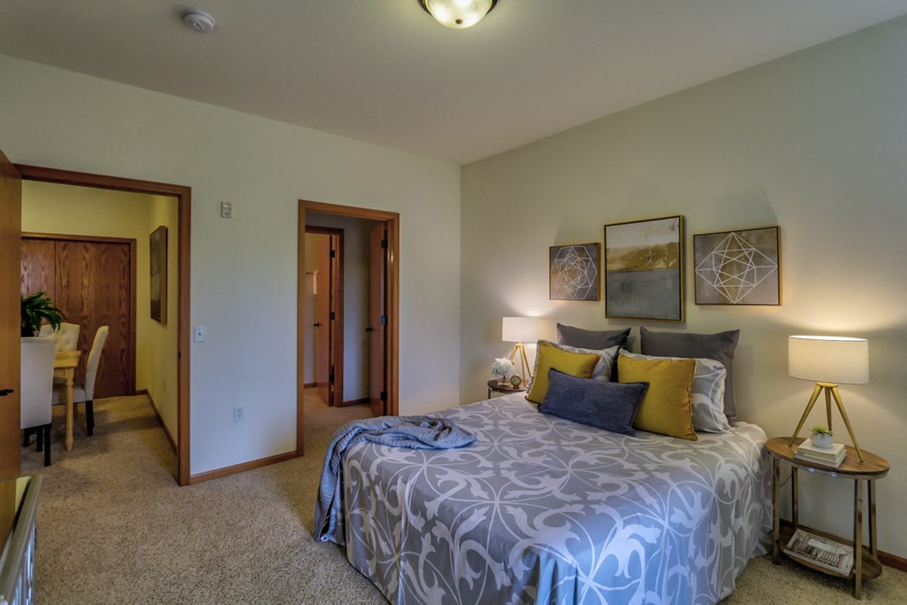 a bedroom with a large bed and a living room with a table and chairs