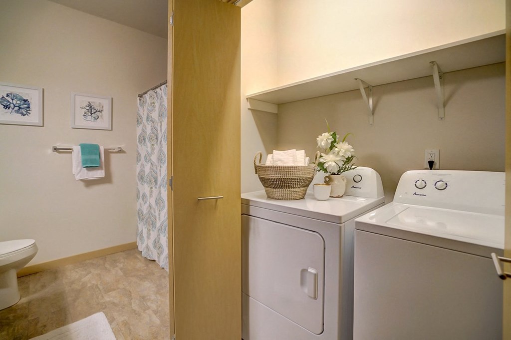 a washer and dryer in a laundry room with a toilet and a shower