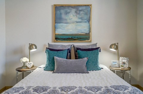 a bedroom with a bed with pillows and a painting on the wall