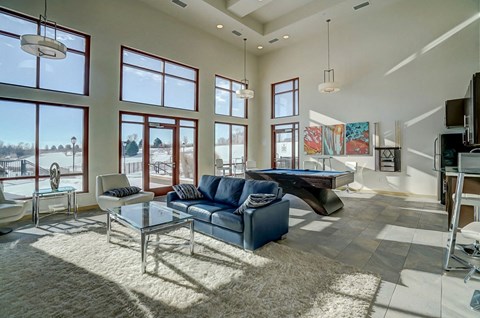 a living room with a pool table and large windows