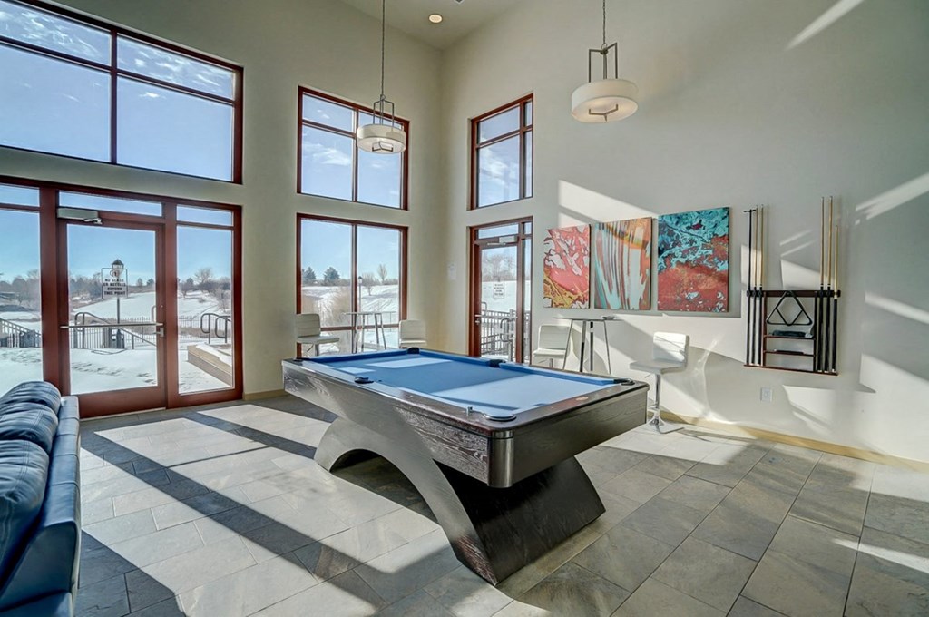 a pool table is in the center of a living room with large windows