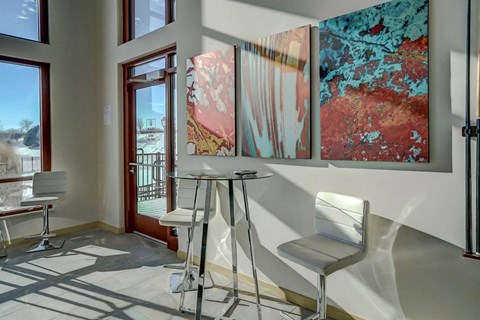 a seating area with three chairs and paintings on the wall