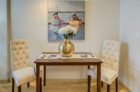 a dining room with a table and chairs and a vase with flowers