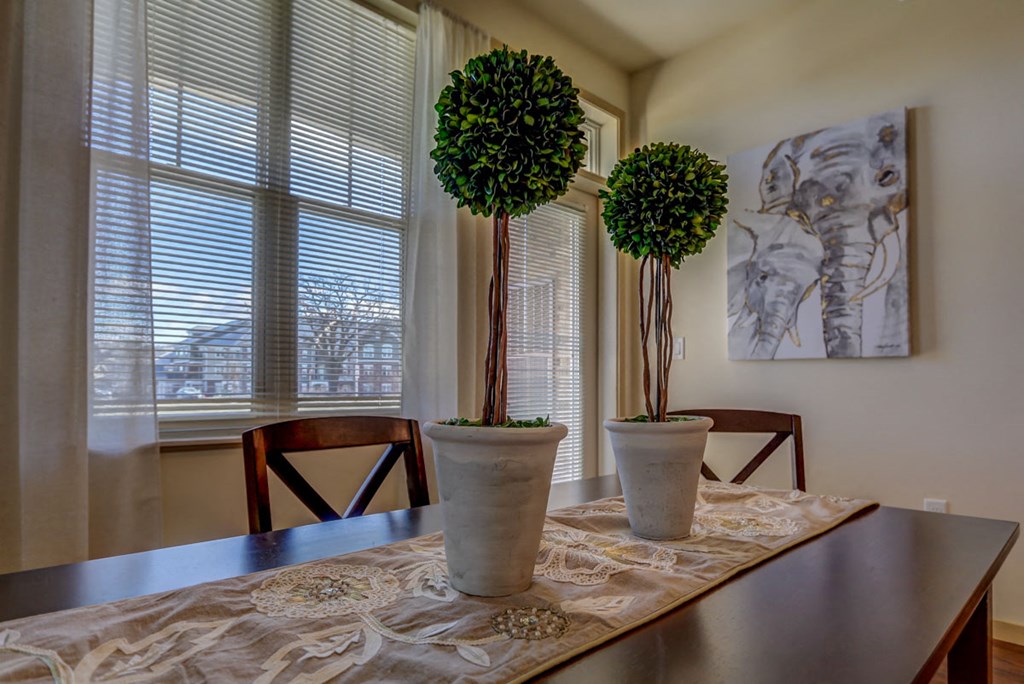 a dining table with three potted plants in front of a window