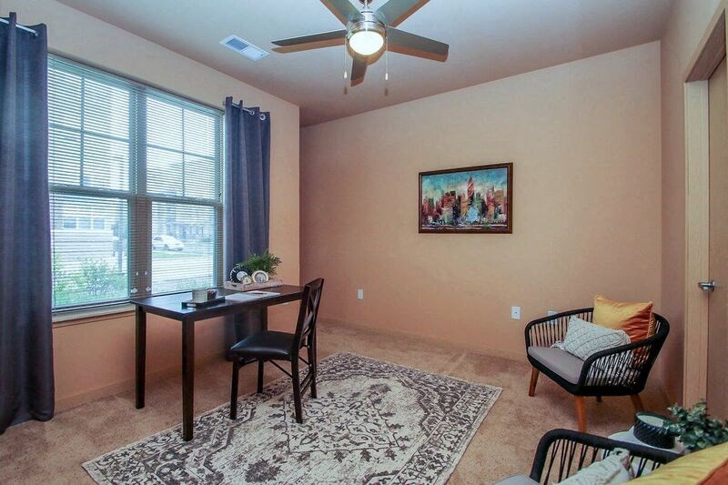 a living room with a table and chairs and a ceiling fan