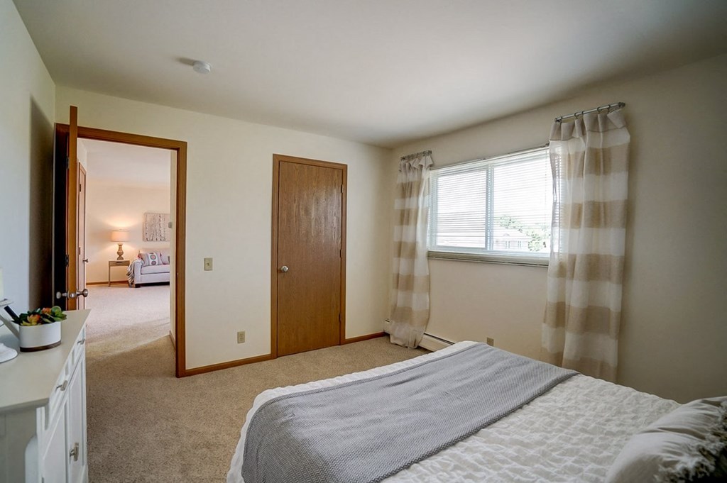 a bedroom with a bed and a door and a window