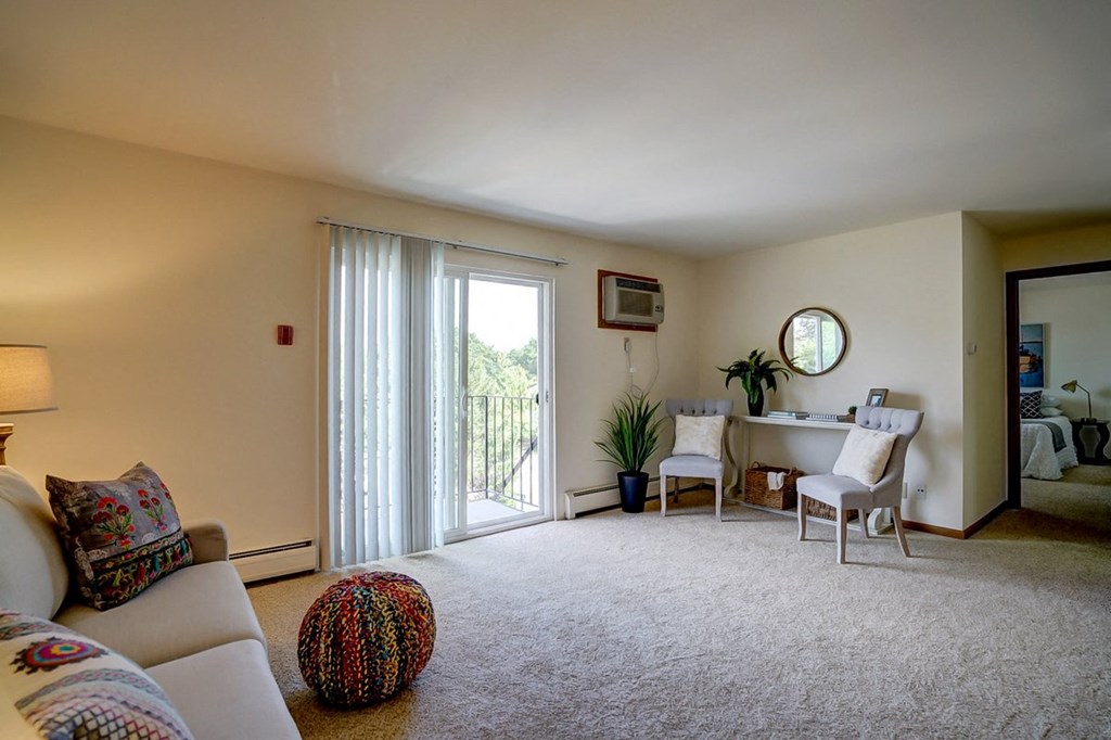 a living room with a couch and a desk and a sliding glass door