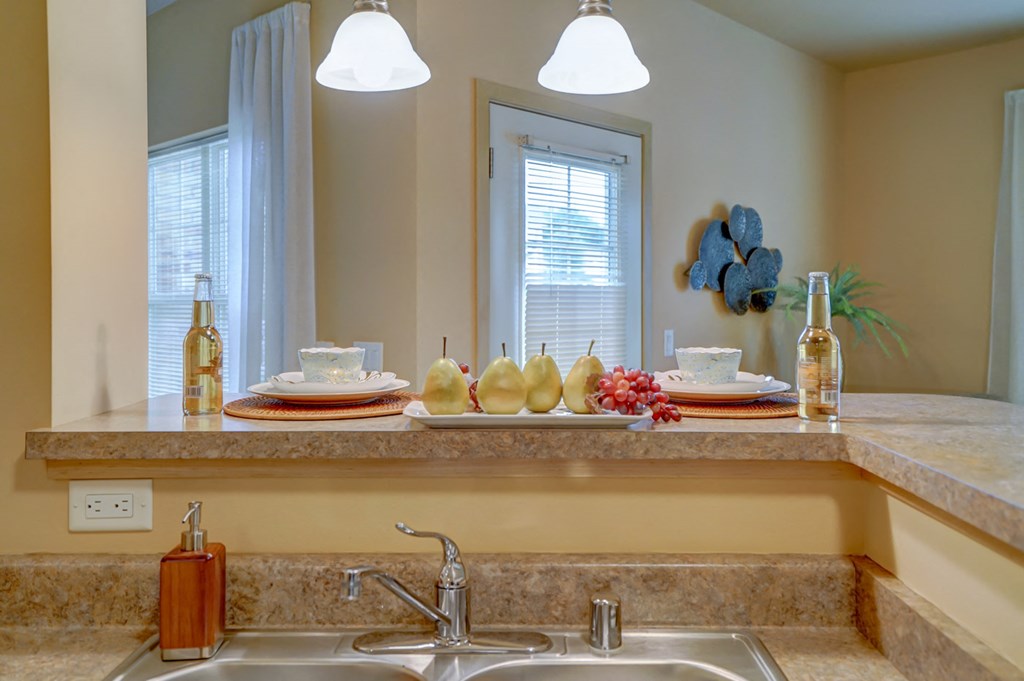 a kitchen with a sink and a window and a counter top with plates and pitchers