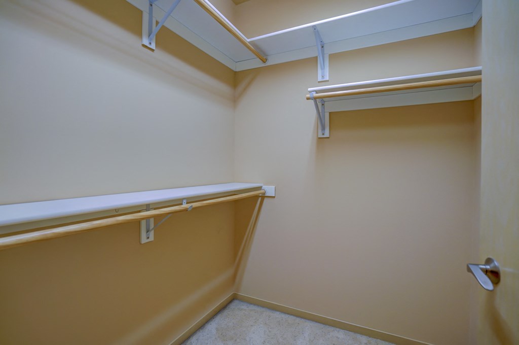 a walk in closet with a mirror and a shelf