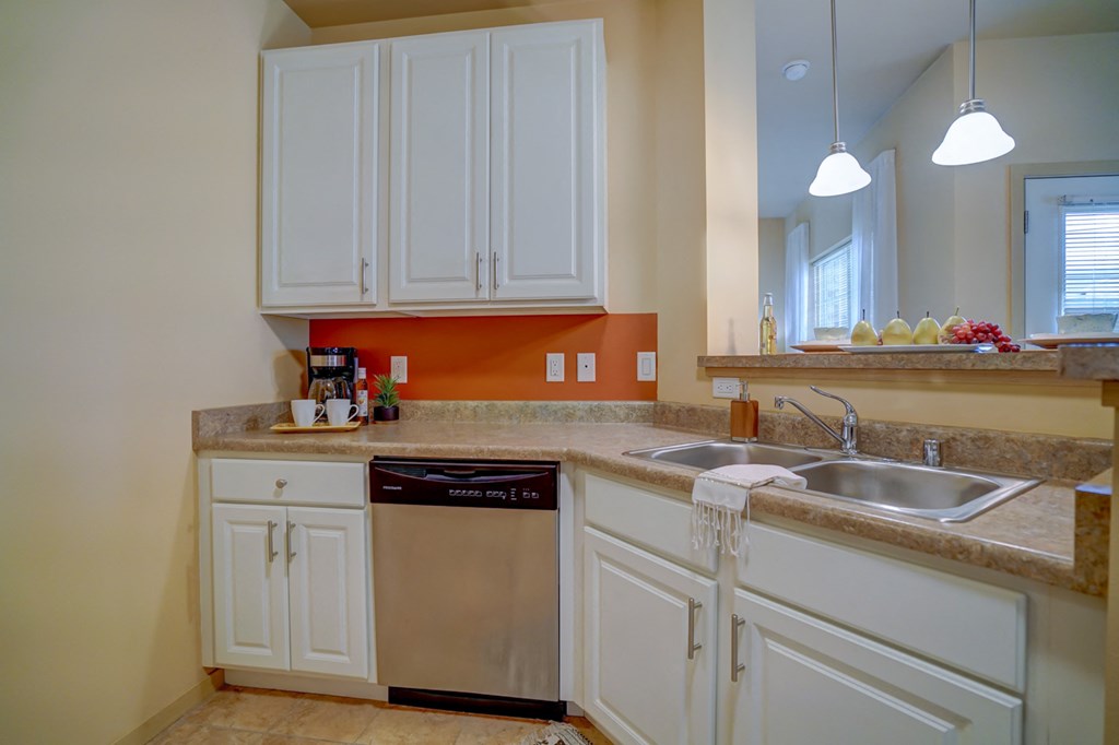a kitchen with white cabinets and a sink and a dishwasher