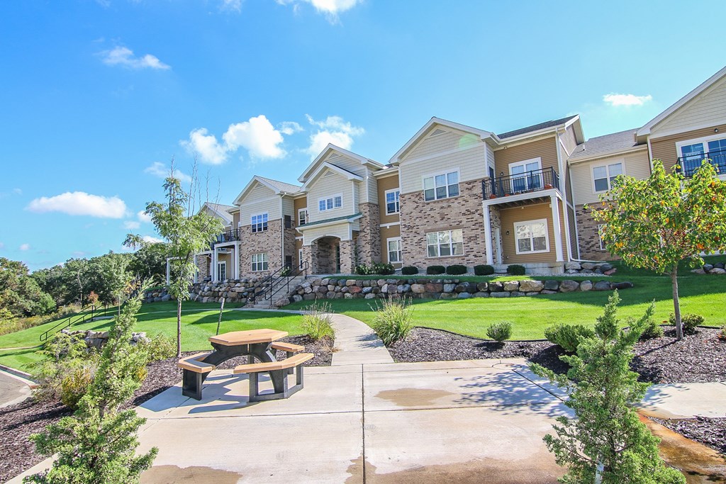 an exterior view of an apartment building with a patio and picnic table