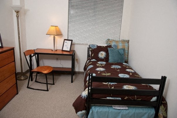 a bedroom with a bed and a desk and a window