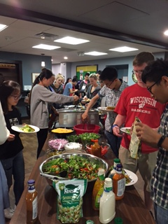 a group of people standing around a buffet table with food
