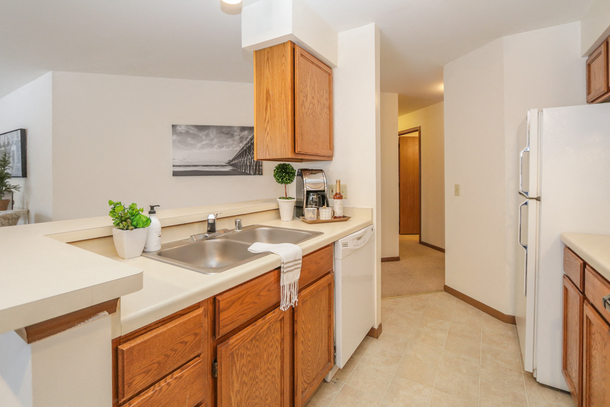 a kitchen with a sink and a refrigerator and a door to a hallway