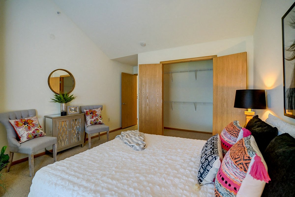 a bedroom with a bed and two chairs and a closet